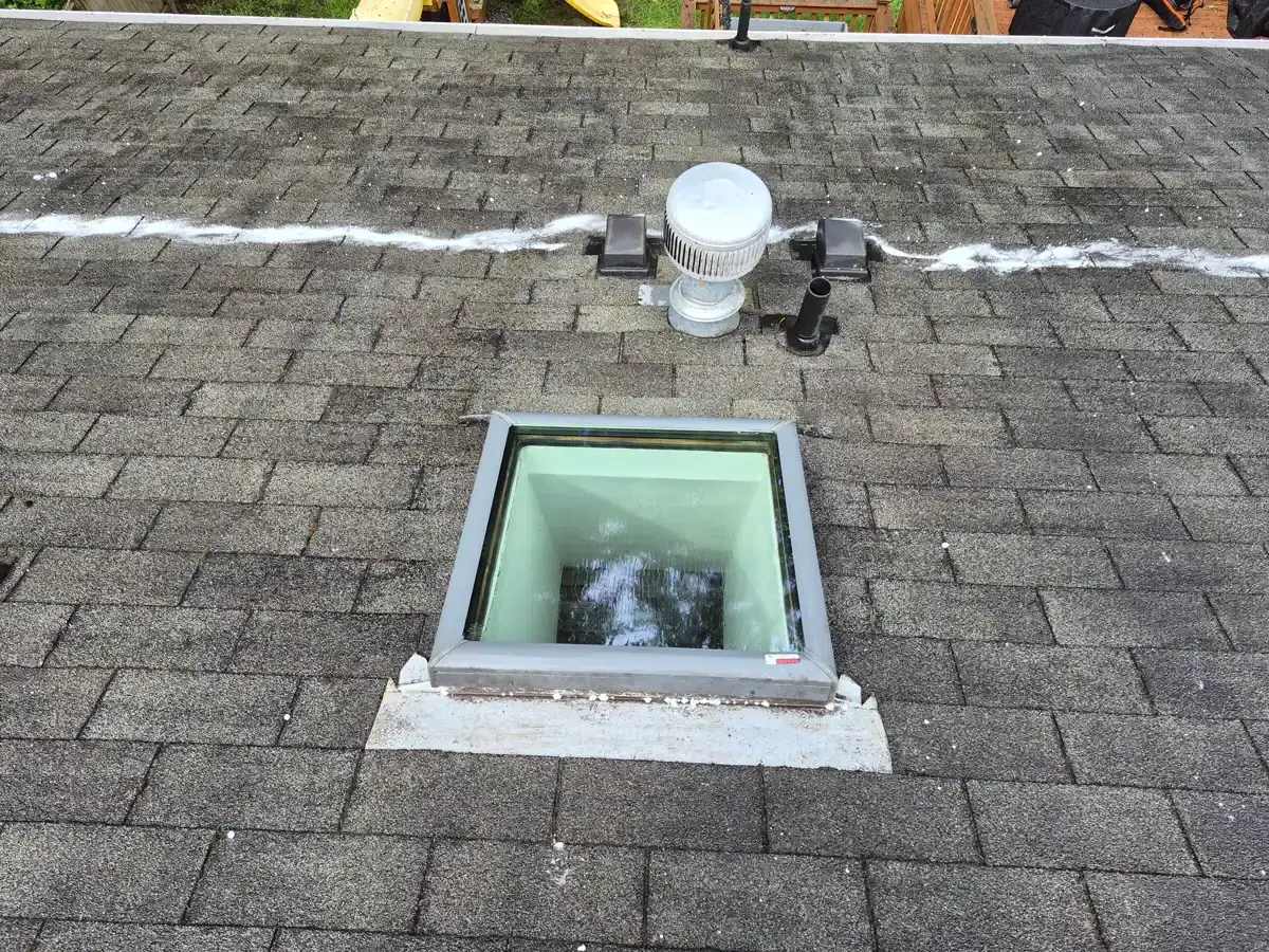 Asphalt shingle roof with skylight silver vent cap and white powder streak after cleaning